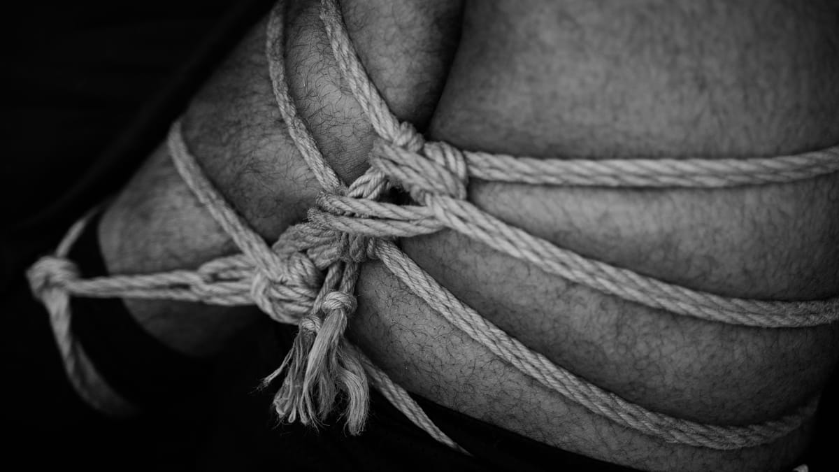 A black and white image of a shibari leg tie