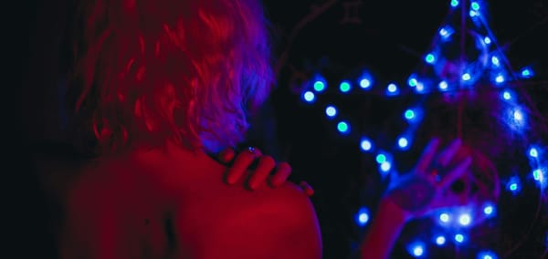 Someone lit with red lighting, standing in front of an LED pentagram